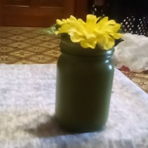 Green mason jar with yellow faux flower on lid
